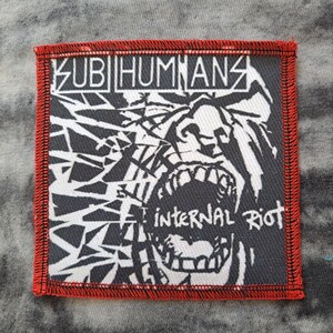 May include: Square patch with a black and white graphic design and red stitched border. The patch features the band name "SUBHUMANS" and the words "INTERNAL RIOT" in white text.