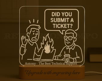 Peut inclure: Lampe LED rectangulaire avec une base en bois. Elle présente une illustration de dessin animé avec le texte "DID YOU SUBMIT A TICKET ?" et "Antony - The Best Technical Support". La base indique "Upgrade with engraving here".