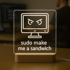 May include: A lighted desktop computer-shaped sign with the text "sudo make me a sandwich". The sign has a wooden base and a white outline of a computer monitor with angry eyes.