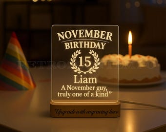 May include: A personalized LED night light with the text "NOVEMBER BIRTHDAY 15 Liam A November guy, truly one of a kind." The light sits on a wooden base. A birthday cake with a lit candle is in the background.