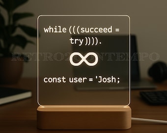 May include: A square, illuminated LED lamp with a wooden base. The lamp displays white text and an infinity symbol. The text reads: "while (((succeed = try)))). const user = 'Josh;" The lamp is plugged in and sits on a wooden surface.