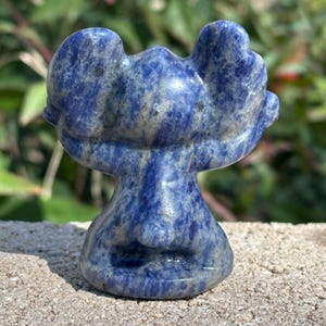 May include: A blue and white carved lapis lazuli sculpture of a moose. The moose is standing on its hind legs with its front legs raised in the air.