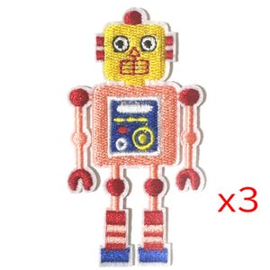 Op de afbeelding: Drie geborduurde strijk-op patches van een cartoon robot met een geel hoofd, roze lichaam, rode armen en benen en blauwe details. De robot heeft een gezicht met twee grote ogen, een kleine neus en een mond.