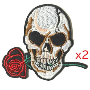 May include: Embroidered patch featuring a skull with a cracked cranium, gold-colored accents, and a red rose held in its teeth. The patch has a black border and the text "x2" in red.