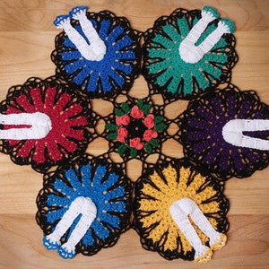 May include: A crocheted doily with a black center and six colorful sections, each featuring a white crocheted figure with legs and arms. The sections are red, blue, green, yellow, purple, and blue.