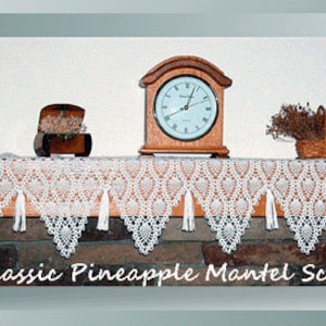 May include: White crocheted mantel scarf with a pineapple pattern and tassels. The scarf is draped over a wooden mantel with a clock, a small wooden box, and a vase of flowers.