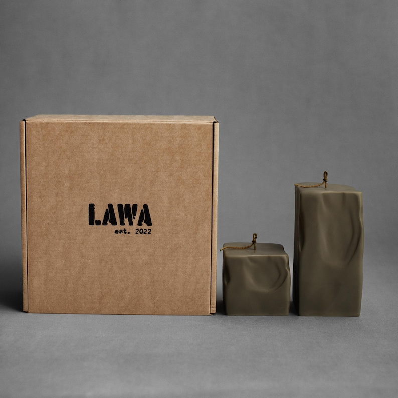 May include: A set of olive green square candles with a textured surface and a small box. The box is brown with the black text "LAWA est. 2022". The candles are different sizes and have a string tied around the top.
