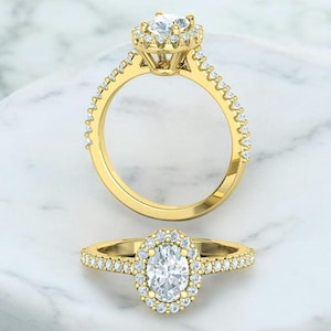 May include: A gold engagement ring with a large oval-shaped diamond surrounded by a halo of smaller diamonds. The band is also set with smaller diamonds.