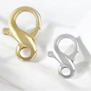 Puede incluir: Dos cierres de langosta, uno plateado y otro dorado, cada uno con un diseño de ocho.