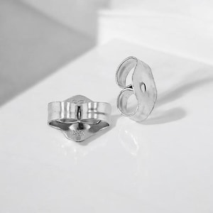 May include: Two silver earring backs, one with a visible marking of "925".