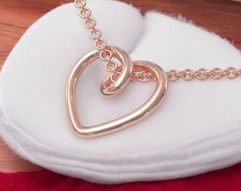 May include: A rose gold necklace with a double heart pendant. The necklace is on a white background.