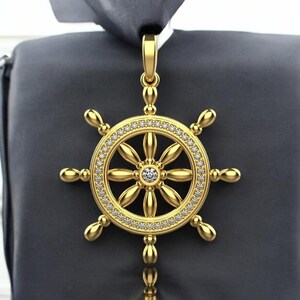 May include: A gold-tone pendant in the shape of a ship's wheel with a clear crystal in the center. The wheel is surrounded by smaller clear crystals.