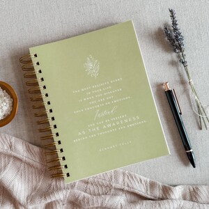 May include: A green spiral bound journal with a quote by Eckhart Tolle: "The most decisive event in your life is when you discover you are not your thoughts or emotions. Instead, you can be present as the awareness behind the thoughts and emotions."