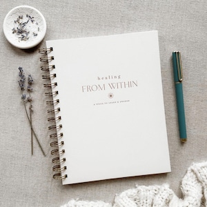 May include: A white spiral bound journal with the text "healing FROM WITHIN" and a small flower graphic. The text below the title reads "A space to learn & awaken".