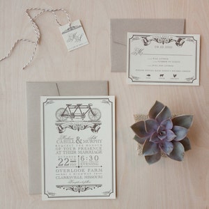 Op de afbeelding: Een beige en witte huwelijksuitnodiging met een zwart-witte illustratie van een tandemfiets. De uitnodiging luidt "Melissa & Seth Cahill & Murphy Request the Honour of Your Presence at Their Marriage October 22nd 2011 6:30 Evening Overlook Farm 901 S Highway 79 Clarksville, Missouri"
