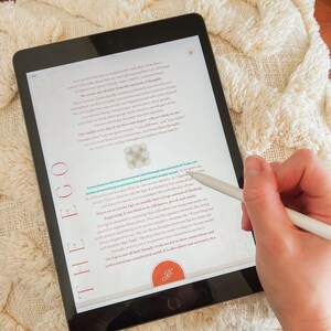 May include: A close-up of a tablet screen displaying text about the ego. The text is in a white font on a black background. The text is about the ego and how it can blind us to our true selves. The text is from the book "A New Earth" by Eckhart Tolle.