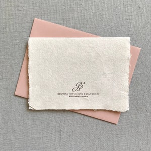 May include: A white card with a pink envelope. The card has a handwritten monogram "JS" and the text "BESPOKE INVITATIONS & STATIONERY @JENSIMPSONDESIGN".