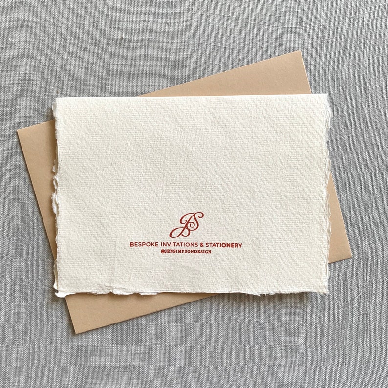May include: A white card with a brown envelope. The card has a red cursive logo that says "Bespoke Invitations & Stationery" and "@jensinfson.design".