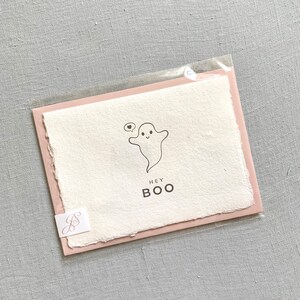 May include: A pink and white card with a cute ghost illustration and the text "Hey Boo".