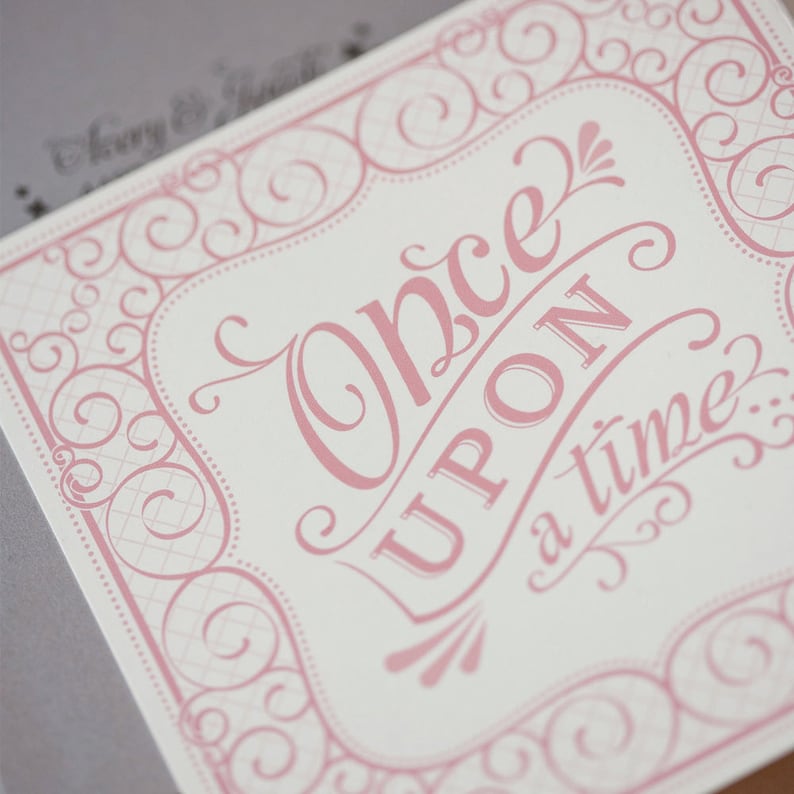 May include: A pink and white card with a decorative border and the text "Once upon a time." in a pink script font.