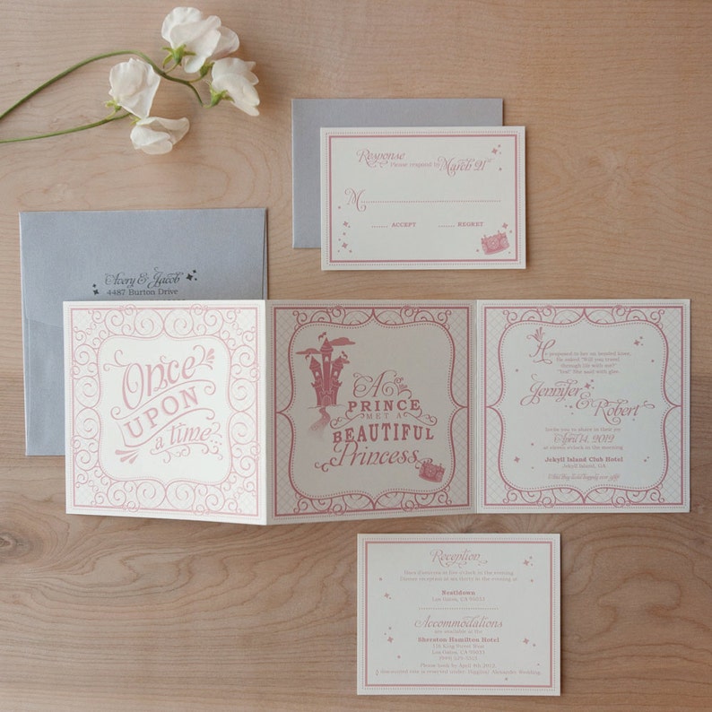 May include: A folded wedding invitation with a pink and white color scheme. The front of the invitation features a pink ornate design with the text "Once Upon a Time". The inside of the invitation features a pink castle illustration with the text "A Prince Met a Beautiful Princess". The back of the invitation features the text "Jennifer & Robert" and the wedding date.