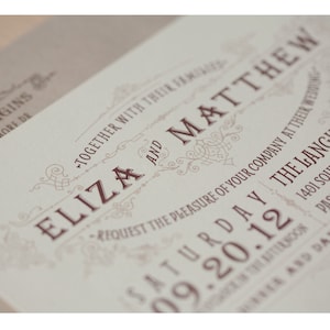 Op de afbeelding: Een huwelijksuitnodiging met een decoratieve rand en de tekst "Eliza en Matthew" in een bruin lettertype. De uitnodiging is voor een huwelijk op zaterdag 20 september 2012.