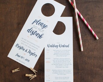May include: A white door hanger with a blue and pink design. The top of the hanger says "Please do not disturb". The bottom of the hanger says "We are recovering from a night of celebrating with the newlyweds Kristin & Taylor June 18, 2018 #KTWEDDING". The right side of the hanger has a schedule for a wedding weekend.