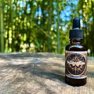May include: A dark brown glass bottle with a black dropper top. The bottle has a label with a gold and black design and the text "Integration" and "Herbal Supplement 1 fl oz".