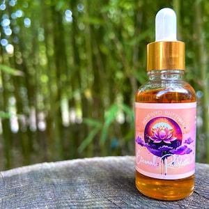 1oz Eternal Radiance beauty serum bottle with a pink & purple label. A vibrant lotus flower sits at the center, surrounded by soft purple clouds, symbolizing renewal and radiance. The design is calming, with a focus on natural beauty & glowing skin.