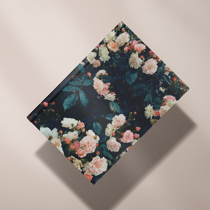 May include: A dark blue notebook cover with a floral pattern featuring pink and white roses and green leaves.