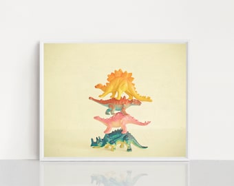 May include: A stack of four colorful plastic dinosaur toys. The dinosaurs are arranged from largest to smallest, with the yellow dinosaur on top and the green dinosaur on the bottom.