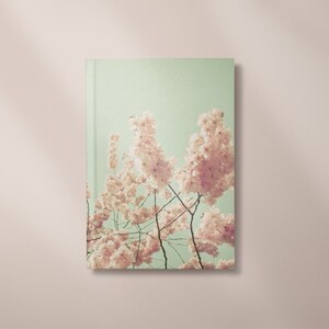 May include: A book cover featuring a photograph of a cluster of pink cherry blossoms against a light green background.