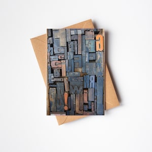 May include: A close-up of a collection of vintage wooden letterpress printing blocks. The blocks are arranged in a random pattern and feature a variety of letters, numbers, and punctuation marks. The blocks are painted in shades of blue, brown, and orange.