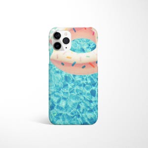 May include: A phone case featuring a pink and white doughnut pool float in a blue swimming pool. The case has a camera cutout.