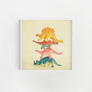 May include: A stack of four colorful plastic dinosaur toys. The dinosaurs are arranged from largest to smallest, with a yellow dinosaur on top, followed by an orange dinosaur, a pink dinosaur, and a blue dinosaur.