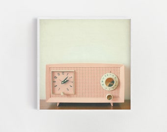 May include: A vintage pink clock radio with a white face and black hands. The radio has a grid pattern on the front and a round dial with numbers.