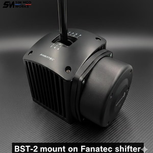 May include: Black Fanatec shifter with a BST-2 mount. The shifter has a black gear stick and a housing with the numbers 2, 4, and 6 visible. The product is designed for sim racing.