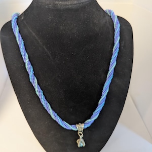 Collar de cuentas de vidrio, en dos tonos azul y morado, con una garra de dragón agarrando un orbe. 24142