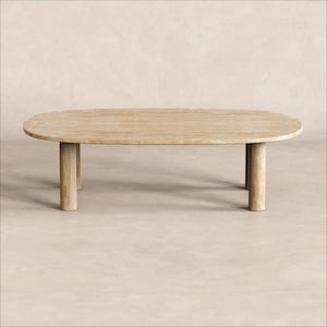 May include: A light-coloured, oval-shaped wooden coffee table. The table has a scalloped edge and four cylindrical legs. The wood grain is visible, and the table has a natural, unfinished appearance. The table is approximately 152 cm long.