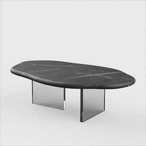 Puede incluir: Una mesa de centro ovalada de mármol negro con una forma orgánica única. La mesa tiene una base de vidrio transparente con dos soportes rectangulares.
