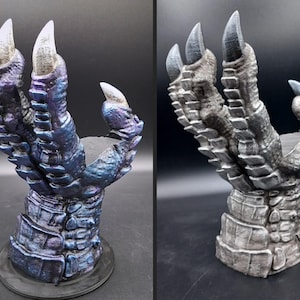 May include: Two dragon claw sculptures, one in blue and purple, the other in grey and silver. Each claw features sharp, white-tipped talons and a textured, scaled design. The sculptures are mounted on a round base, suitable for display.