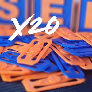 Puede incluir: Un montón de clips de plástico naranja y azul. Los clips tienen forma rectangular con un detalle de tornillo central. La imagen también presenta el texto blanco "X20". El fondo muestra formas borrosas naranjas y azules.