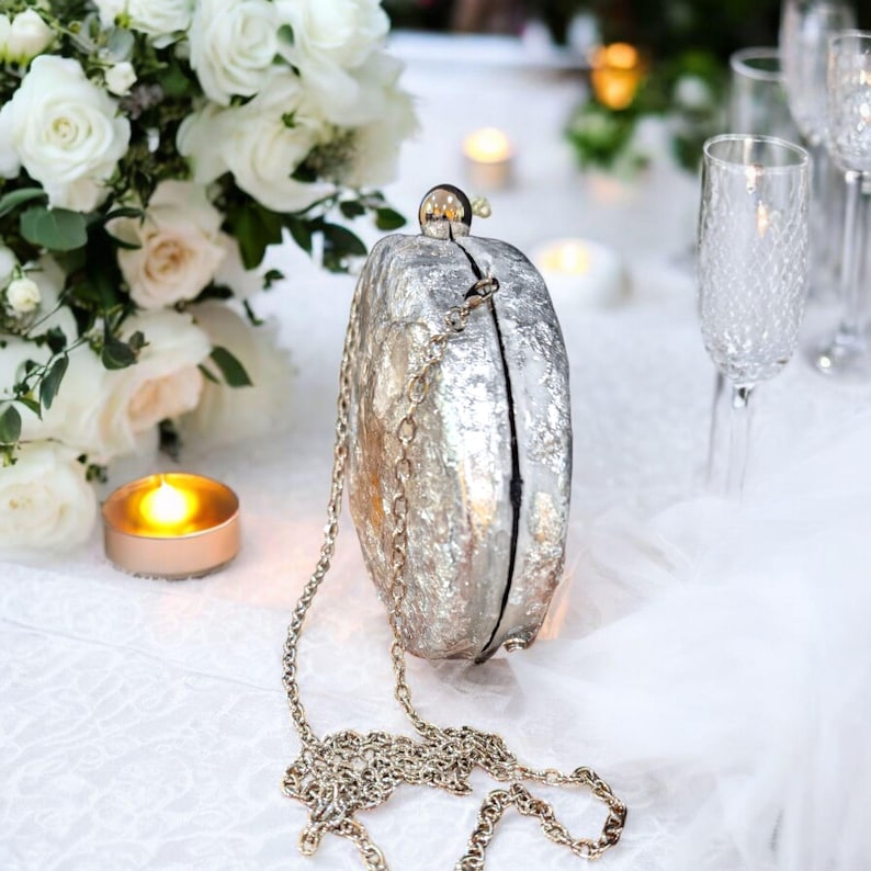 Woman Clutch Bag—Designer Bag, Handmade Bag, Statement-Fashion, Fancy Bags for Women, Women's Small Bag Clutch, Gift Her!. Bridal Clutch Bag—Mother of Peral style bag This oval-shaped hard shell clutch is not just a bag; it's a conversation starter meticulously designed to echo the breathtaking textures of the moon's landscape. Its pristine white exterior glimmers softly, capturing the light and reflecting it in a way that draws attention without saying a word. Handmade in USA. Mothers day gift