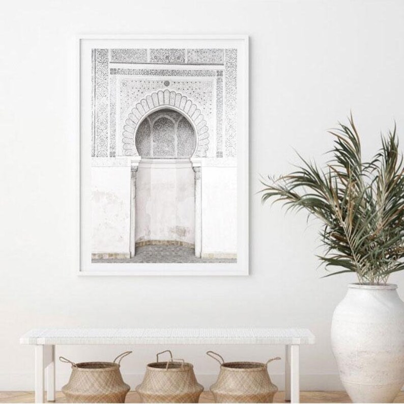 Puede incluir: Fotograf&iacute;a en blanco y negro de un arco tradicional marroqu&iacute; con intrincados detalles. El arco est&aacute; enmarcado por una pared blanca y tiene un patr&oacute;n decorativo encima.