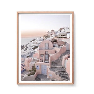 May include: A pastel pink and white building with a blue door and stone steps leading up to it. The building is situated on a hillside overlooking the ocean.