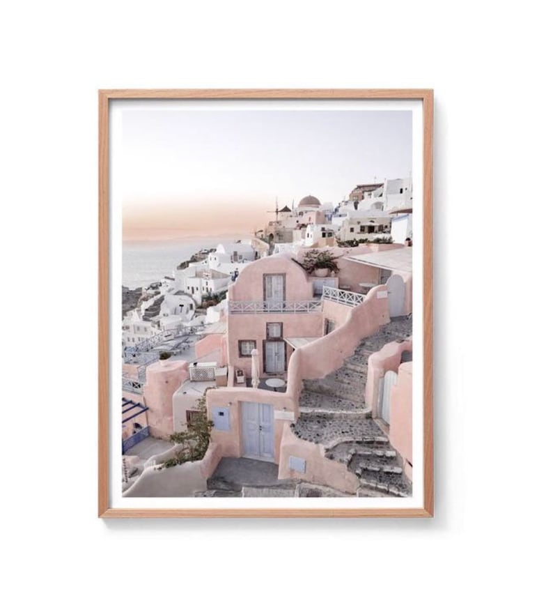 May include: A pastel pink and white building with a blue door and stone steps leading up to it. The building is situated on a hillside overlooking the ocean.