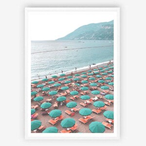 May include: A beach scene with turquoise umbrellas and orange lounge chairs on a sandy beach. The beach is lined with turquoise water and a mountain range in the distance.