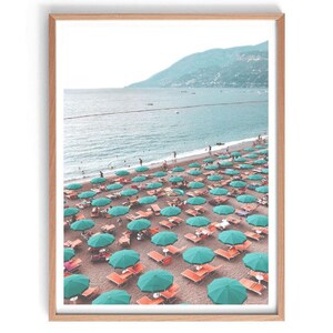 May include: A beach scene with turquoise umbrellas and orange lounge chairs on a sandy beach. The beach is lined with turquoise water and a green mountain in the background.