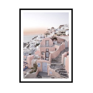 May include: A pink and white building with a blue door and a stone staircase in a village overlooking the ocean. The building has a balcony and a white railing. The sky is a light blue with a few clouds.