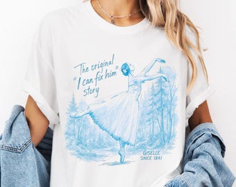 May include: A white short-sleeve t-shirt featuring a blue graphic of a ballerina in a forest. The text reads: The original "I can fix him" story GISELLE SINCE 1841. The shirt has a crew neckline and is worn with a light blue denim jacket.